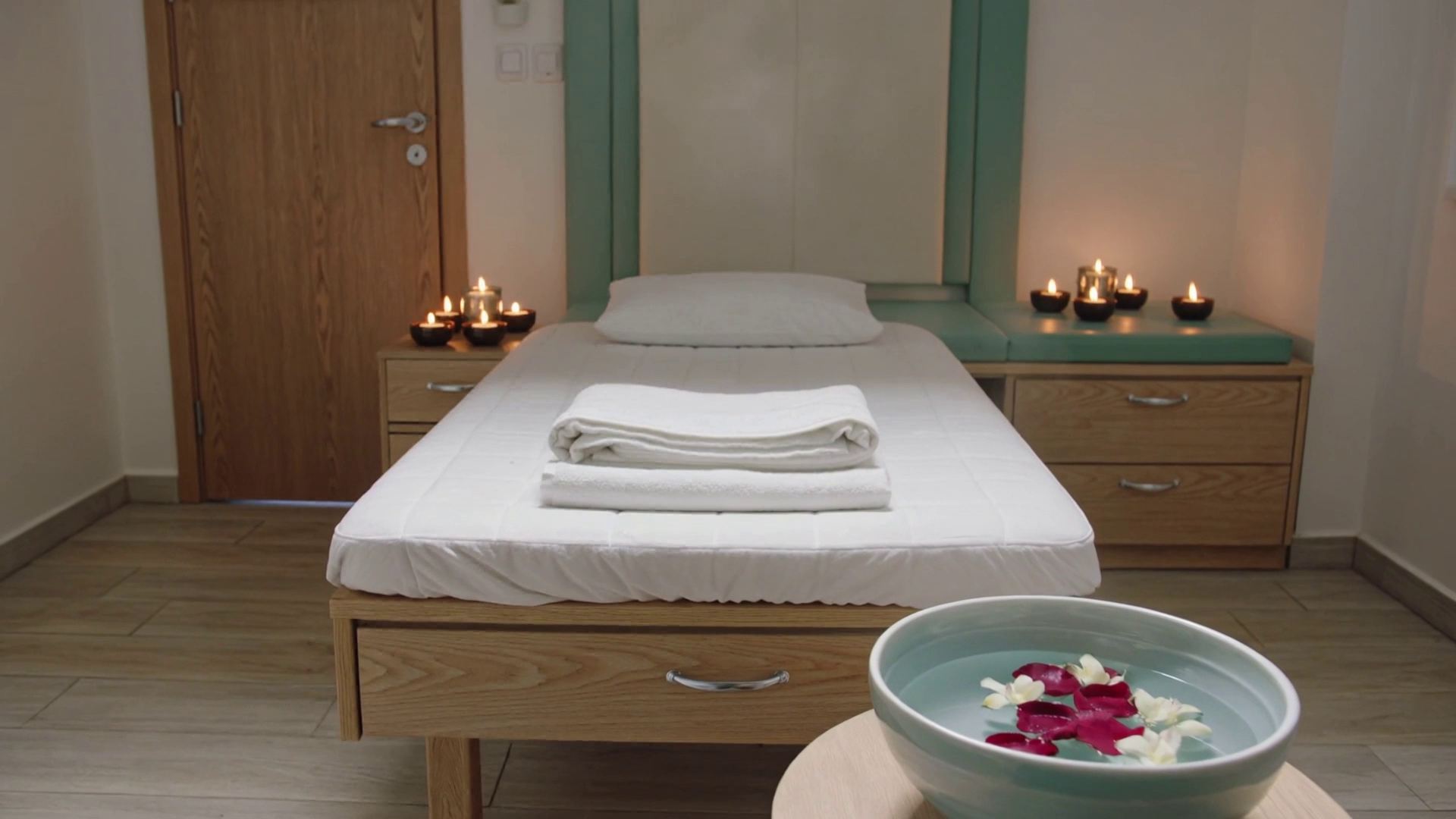 A treatment room with folded towels and lit candles
