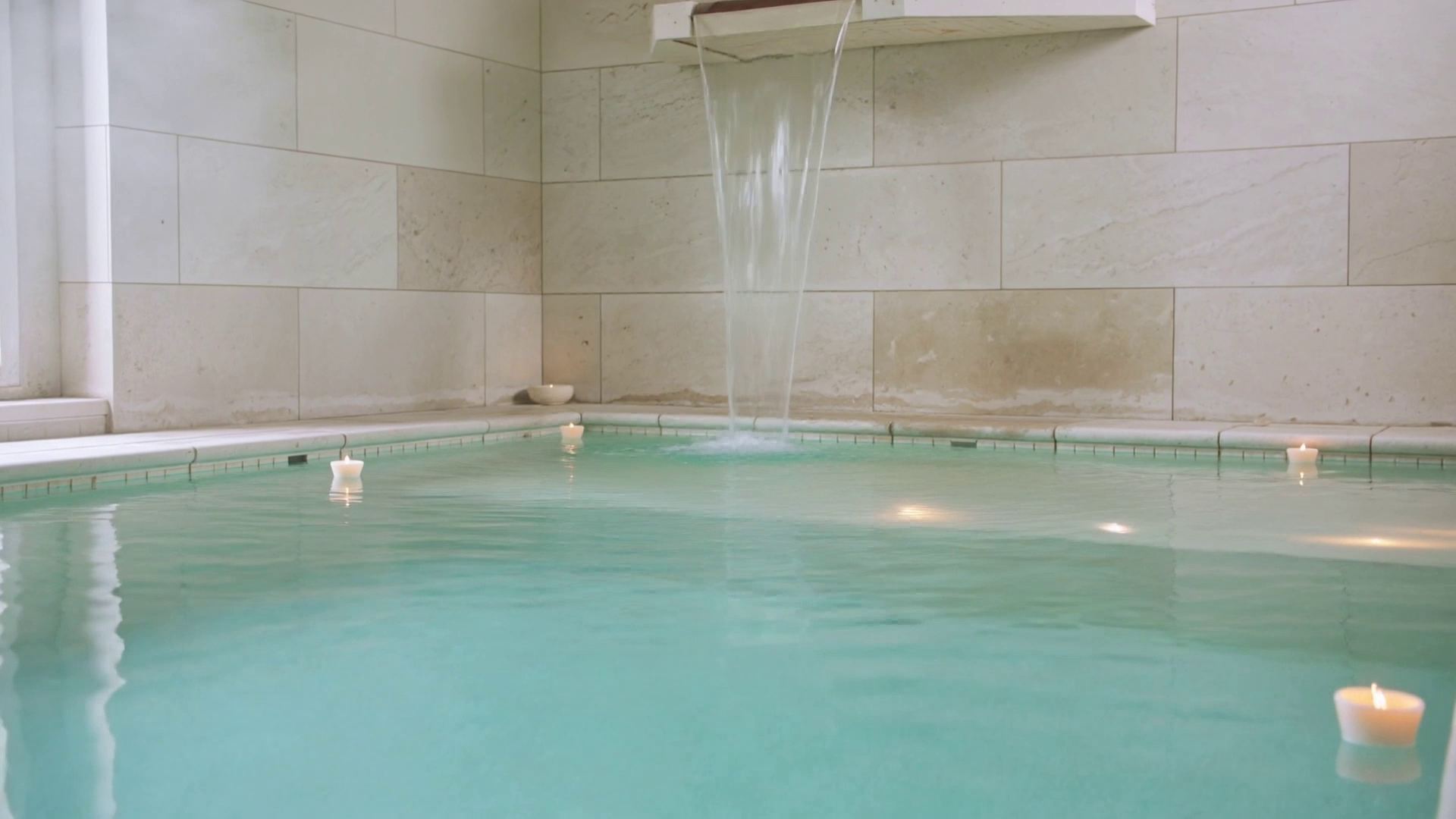 An indoor pool with a waterfall falling from the wall